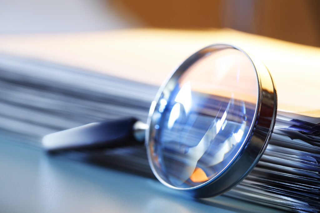 Magnifying Glass Leaning Against Stack Of Papers