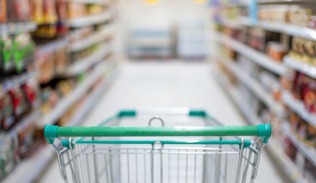 shortages Supermarket aisle with empty silver and green shopping trolley, Shopper choosing the food in supermarket